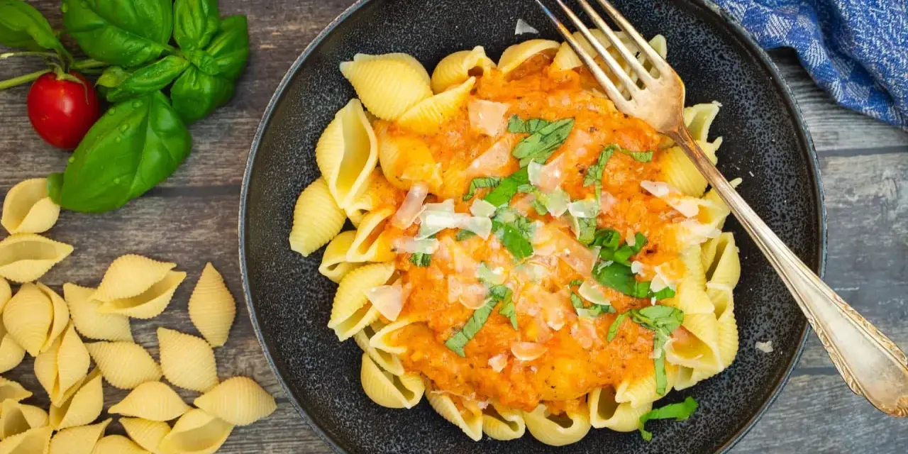 Schalen-Nudeln mit cremiger Tomaten-Sahne-Sauce, garniert mit Basilikum und Parmesan. Ein köstliches Gericht, das zum Genießen einlädt.