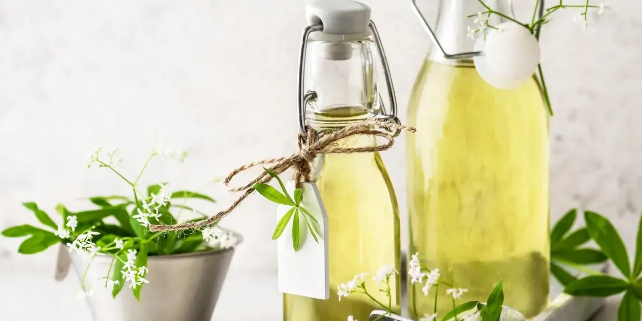 Zwei Flaschen mit selbstgemachtem Waldmeistersirup, dekoriert mit frischem Waldmeister.