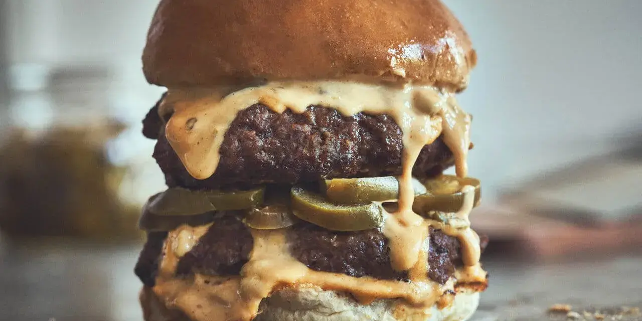 Ein saftiger Chili Cheese Burger mit zwei Patties, geschmolzener Käsesauce und Jalapeños.