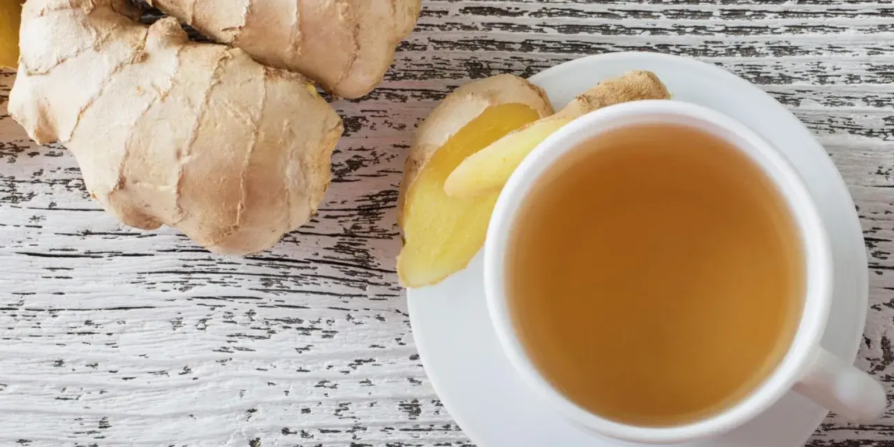 Frischer Ingwer und eine Tasse Ingwertee auf Holzhintergrund. Vielleicht ein kleiner Fehler bei der Zubereitung, wenn der Tee zu stark ist.