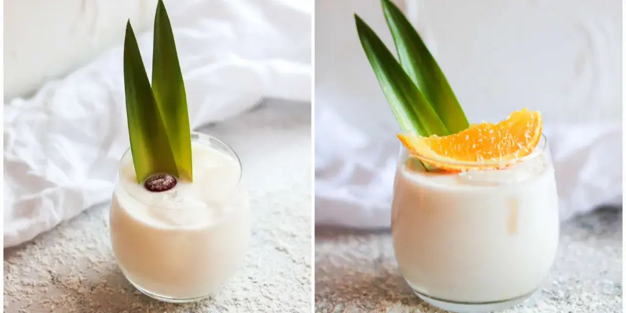 Zwei Gläser cremiger, alkoholfreier Piña Colada, garniert mit Ananasblättern und einer Orangenscheibe bzw. einer Beere.