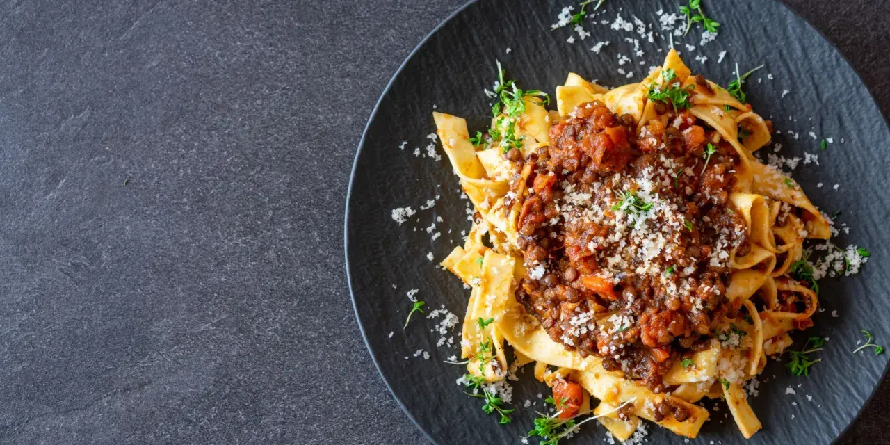 Jamie Oliver Bolognese auf Bandnudeln, garniert mit frischen Kräutern und Parmesan. Ein herzhaftes Gericht, das Lust auf mehr macht.