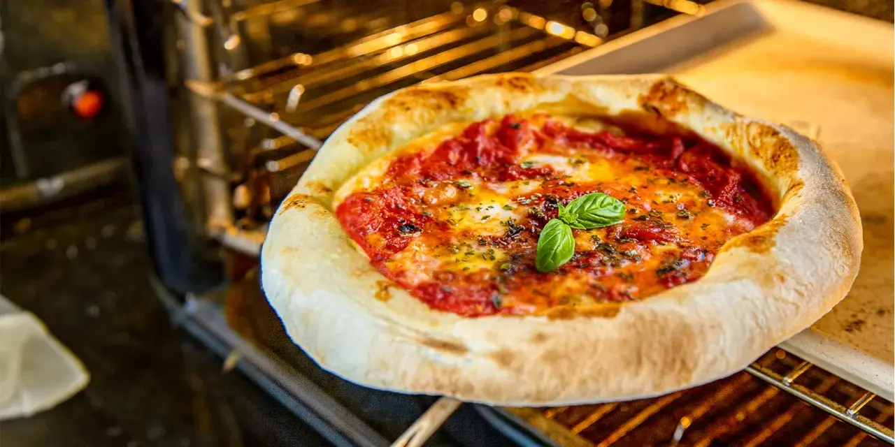 Frisch gebackene neapolitanische Pizza mit Tomaten, Mozzarella und Basilikum im Ofen. Ein perfektes neapolitanische Pizza Rezept.