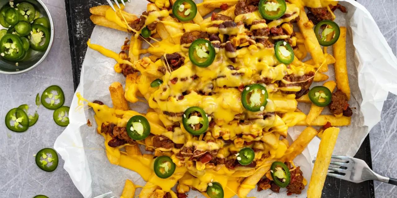 Pommes Frites mit Hackfleisch, Bohnen, Mais und geschmolzenem Käse, garniert mit Jalapeños. Ein köstliches Gericht mit **Chilli Cheese Sauce**.