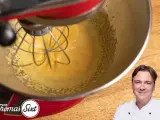 Küchenmaschine mixt eine cremige, gelbe Masse, die an Sauce Hollandaise erinnert. Ein Koch lächelt im Vordergrund.