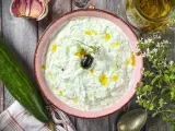 Frischer Tzatziki selbst machen: Cremiger Joghurt mit Gurke, Knoblauch, Dill und Olivenöl. Dazu eine Olive und Kräuter.
