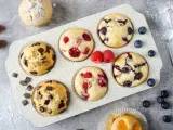 Leckeres Muffins Rezept: Schoko-, Himbeer- und Blaubeermuffins in einer Form, daneben frische Beeren und Schokostückchen.