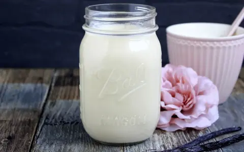 Selbstgemachter Kaffee-Sirup in einem Glas, mit Vanilleschoten und einer rosa Blume. Perfekt zum Kaffee creamer selber machen.