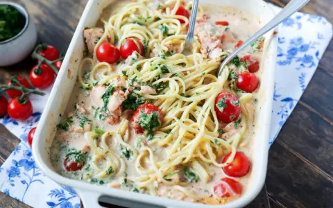 Cremige Lachs Spinat Pasta mit Kirschtomaten in einer Auflaufform, bereit zum Servieren.
