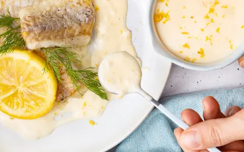 Gebratenes Fischfilet mit Zitronen-Butter-Sauce, garniert mit Dill und Zitronenscheibe.