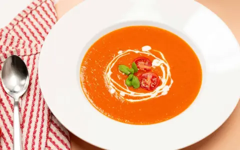 Ein Teller cremiger Tomatensuppe, garniert mit frischen Tomaten und Basilikum. Perfekt für ein einfaches Tomatensuppe Rezept mit frischen Tomaten.