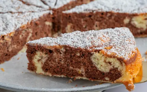 Ein Stück saftiger Marmorkuchen, bestäubt mit Puderzucker. Dieses fluffiger wolkenkuchen rezept ist ein Genuss!