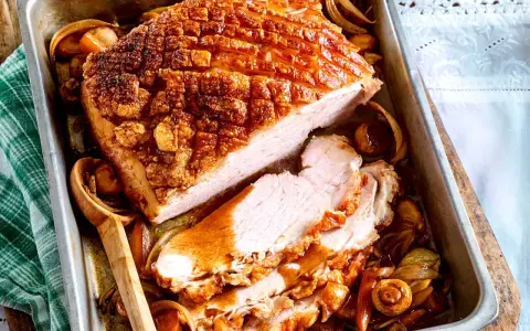 Saftiger Krustenbraten im Backofen, goldbraun und knusprig, mit Zwiebeln und Pilzen im Bratensaft. Ein Festmahl!