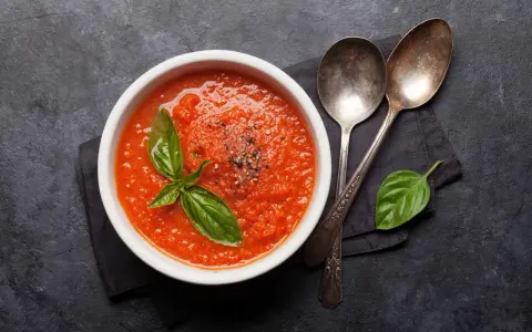 Schüssel mit frischer Tomatensuppe, garniert mit Basilikum. Perfekt, um Tomatensauce selber machen zu lernen.