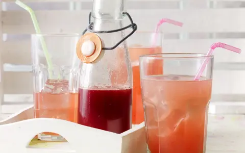 Erfrischender Rhabarbersirup im Glas mit Eis und Strohhalm. Ein tolles Rezept für den Sommer!