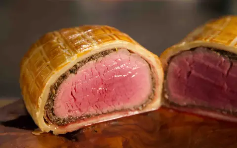 Ein perfekt zubereitetes Beef Wellington, saftig rosa im Inneren, umhüllt von goldbraunem Blätterteig.