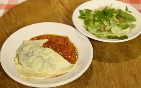 Ein Teller mit Maultaschen in Tomatensoße und ein kleiner Salat. Perfekt für ein schnelles Maultaschen Rezept.