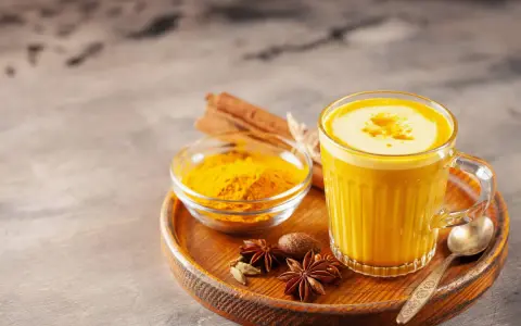 Ein Glas goldene Milch mit Kurkumapulver, Zimtstangen und Sternanis. Perfekt für ein wärmendes goldene milch rezept.