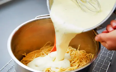 Cremige Käsesauce wird über Spaghetti gegossen. Ein einfaches Käsesauce Rezept für ein köstliches Gericht.