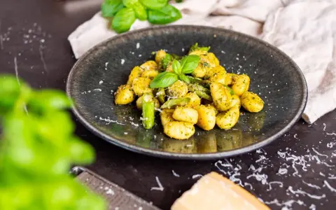 Gnocchi mit Spargel, garniert mit frischem Basilikum und Parmesan. Ein köstliches Gericht, das den Frühling auf den Teller bringt.