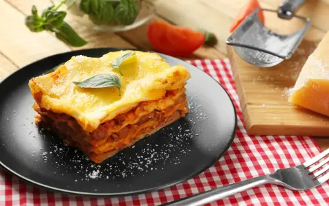 Ein Stück Lasagne mit Käse überbacken, garniert mit Basilikum. Perfekt für ein köstliches Lasagne Rezept.
