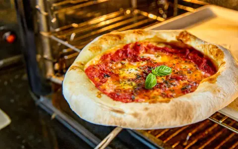 Frisch gebackene neapolitanische Pizza mit Tomaten, Mozzarella und Basilikum im Ofen. Ein perfektes neapolitanische Pizza Rezept.