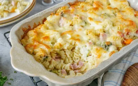 Nudelauflauf mal anders: Fusilli mit Schinken, Brokkoli und Karotten, überbacken mit goldbraunem Käse in einer Auflaufform.