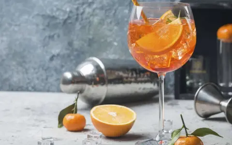 Erfrischender Aperol Spritz mit Orangenscheiben und Eiswürfeln, garniert mit Rosmarin. Ein Hauch von Sommer.
