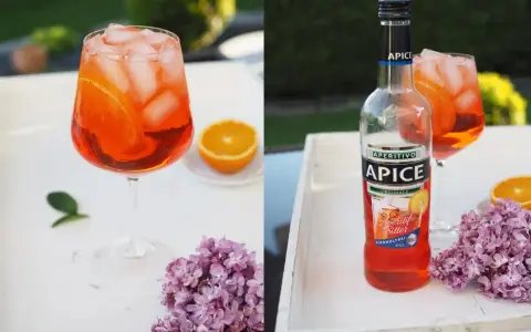 Erfrischender alkoholfreier Aperol mit Eis und Orangenscheiben, daneben eine Flasche Apice Aperitif Bitter.