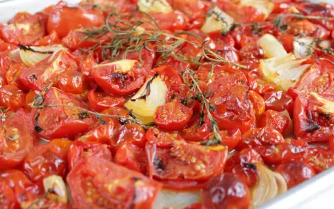 Tomatensauce aus dem Ofen: Geröstete Tomaten und Zwiebeln mit Rosmarin, die köstlich duften und bereit sind, zu einer aromatischen Sauce verarbeitet zu werden.