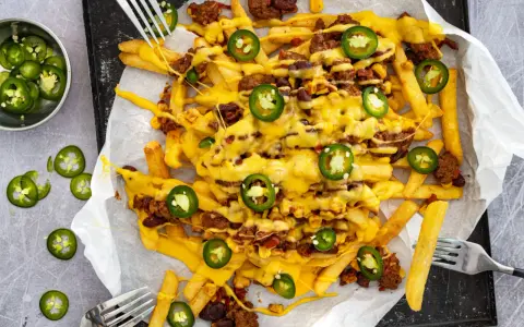 Pommes Frites mit Hackfleisch, Bohnen, Mais und geschmolzenem Käse, garniert mit Jalapeños. Ein köstliches Gericht mit **Chilli Cheese Sauce**.