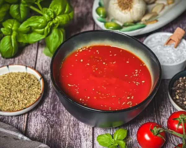 Frische Zutaten für Pizzasauce selber machen: Tomaten, Basilikum, Knoblauch, Oregano, Salz und Pfeffer.