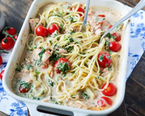 Cremige Lachs Spinat Pasta mit Kirschtomaten in einer Auflaufform, bereit zum Servieren.
