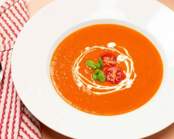 Ein Teller cremiger Tomatensuppe, garniert mit frischen Tomaten und Basilikum. Perfekt für ein einfaches Tomatensuppe Rezept mit frischen Tomaten.