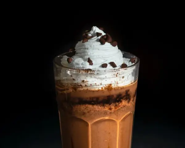 Eiskaffee selbst machen: Ein Glas mit cremigem Eiskaffee, Sahne und Schokostückchen. Perfekt für heiße Tage!