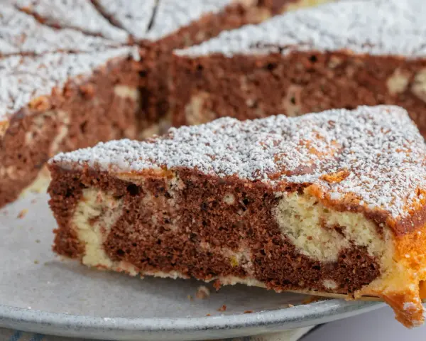 Ein Stück saftiger Marmorkuchen, bestäubt mit Puderzucker. Dieses fluffiger wolkenkuchen rezept ist ein Genuss!