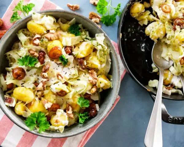 Leckeres rezept mit spitzkohl, Kartoffeln, Datteln und Walnüssen in cremiger Soße, garniert mit Petersilie.