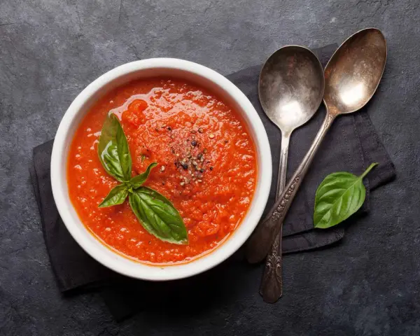 Schüssel mit frischer Tomatensuppe, garniert mit Basilikum. Perfekt, um Tomatensauce selber machen zu lernen.
