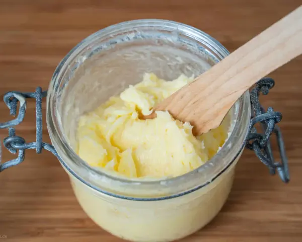 Frisch gemachte Butter in einem Glas, mit einem Holzspatel zum Butter selber machen.