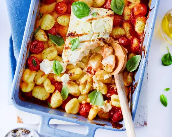 Gnocchi-Pfanne mit Feta, Kirschtomaten und Basilikum in einer blauen Auflaufform, bereit zum Servieren.