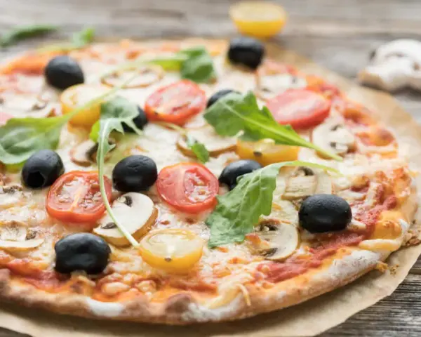 Leckerer Pizzaboden mit Joghurt, belegt mit Tomaten, Oliven und Pilzen.
