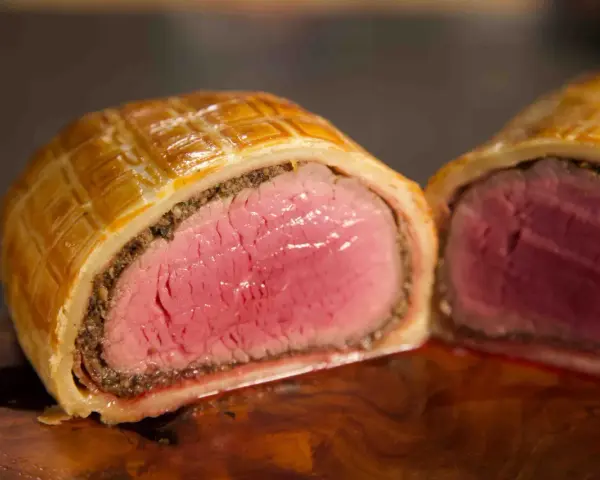 Ein perfekt zubereitetes Beef Wellington, saftig rosa im Inneren, umhüllt von goldbraunem Blätterteig.