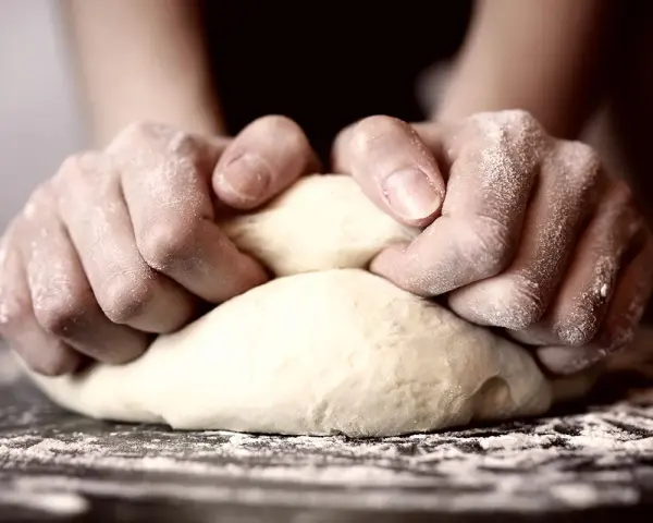 Hände kneten den pizzateig. Wie lange kneten? Bis er geschmeidig ist!