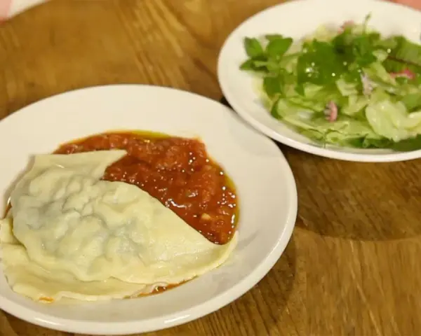 Ein Teller mit Maultaschen in Tomatensoße und ein kleiner Salat. Perfekt für ein schnelles Maultaschen Rezept.