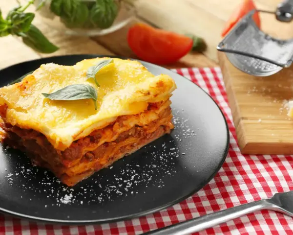Ein Stück Lasagne mit Käse überbacken, garniert mit Basilikum. Perfekt für ein köstliches Lasagne Rezept.