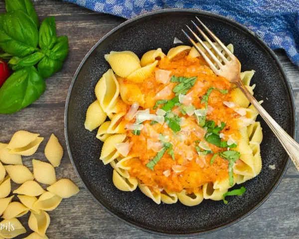 Schalen-Nudeln mit cremiger Tomaten-Sahne-Sauce, garniert mit Basilikum und Parmesan. Ein köstliches Gericht, das zum Genießen einlädt.