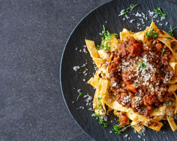 Jamie Oliver Bolognese auf Bandnudeln, garniert mit frischen Kräutern und Parmesan. Ein herzhaftes Gericht, das Lust auf mehr macht.