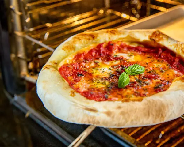 Frisch gebackene neapolitanische Pizza mit Tomaten, Mozzarella und Basilikum im Ofen. Ein perfektes neapolitanische Pizza Rezept.