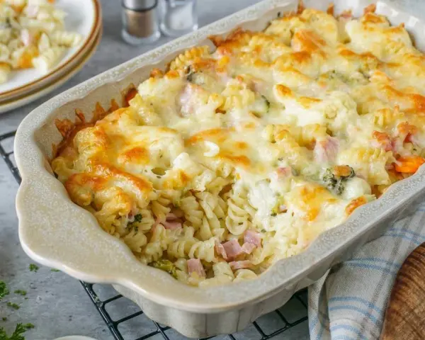 Nudelauflauf mal anders: Fusilli mit Schinken, Brokkoli und Karotten, überbacken mit goldbraunem Käse in einer Auflaufform.