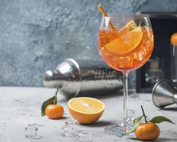 Erfrischender Aperol Spritz mit Orangenscheiben und Eiswürfeln, garniert mit Rosmarin. Ein Hauch von Sommer.